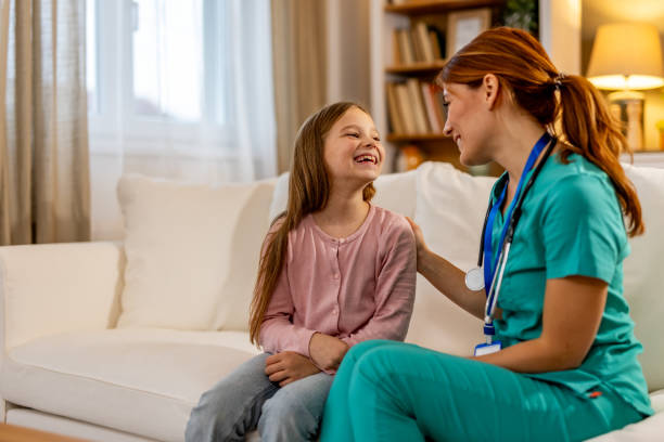 istock Health Professional Interacting Happily With Young Patient in Home Setting 2191463776
