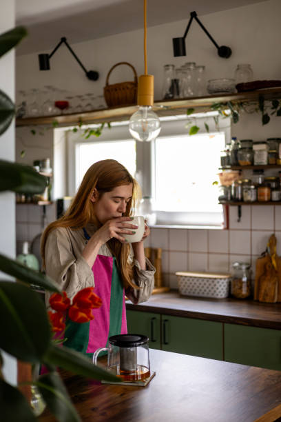 istock Woman drinking tea in cozy kitchen with plants and spices 2191469705