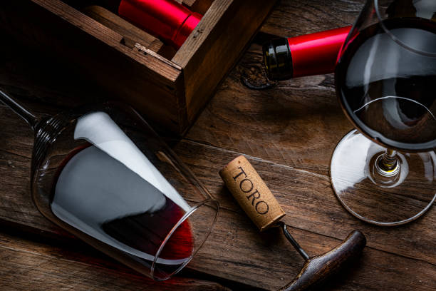 istock Red wineglass and bottles, TORO cork stopper and corkscrew on rustic wooden table 2191472878