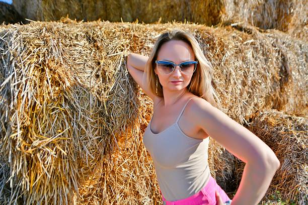 A beautiful woman is resting in the hayloft on a bright, hot, sunny day in the last month of summer.