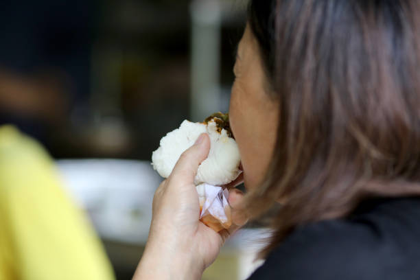An Asian senior woman is enjoying freshly steamed bun