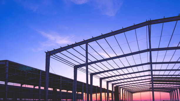 istock Silhouette 2 industrial warehouse buildings framework with metal posts and roof beam structure in factory construction site against twilight sky background 2191481397