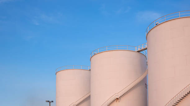 istock Three storage fuel tanks in petrochemical refinery area with orange sunlight on surface against blue evening sky background, low angle view 2191481410