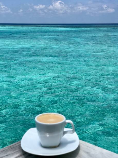 Espresso coffee, Maldives, Indian Ocean view with white mug and saucer and sky cloud