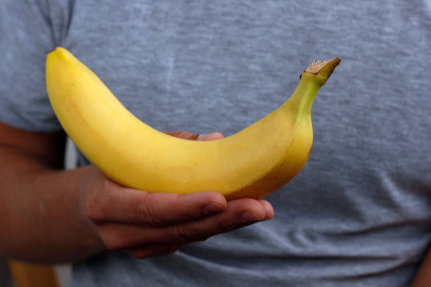 istock banana in hand, man peeling banana 2191483927
