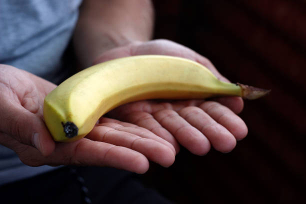 istock banana in hand, man peeling banana 2191483941