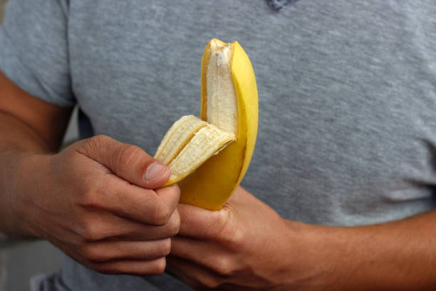 istock banana in hand, man peeling banana 2191483961