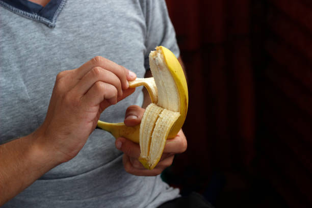istock banana in hand, man peeling banana 2191483966