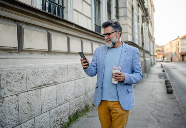 istock Man walking down the street and checking cellphone 2191486313