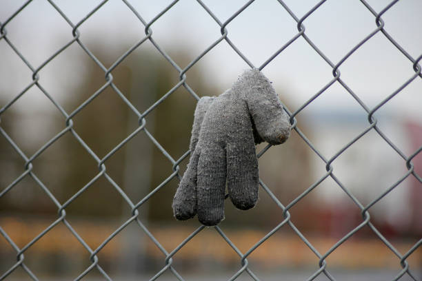 A grey forgotten mitten hanging in a fence