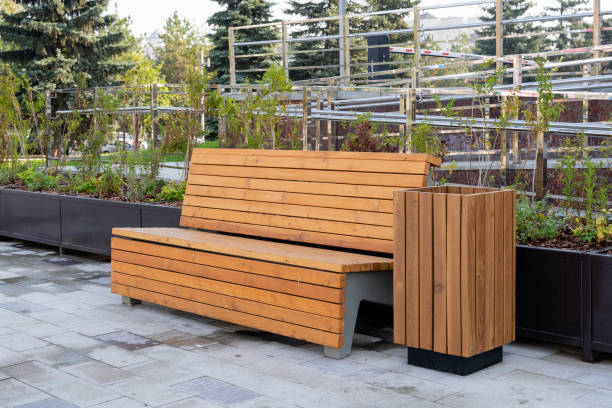 istock In a serene park, there exists a charming wooden bench complemented by a conveniently placed trash can right beside it, providing a perfect spot to relax and enjoy nature 2191487357