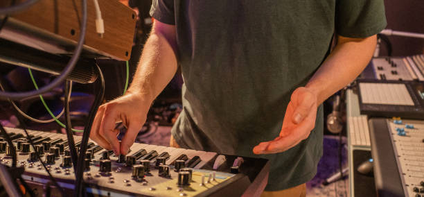 istock music producer adjusting knobs on a synthesizer in a recording studio 2191488303