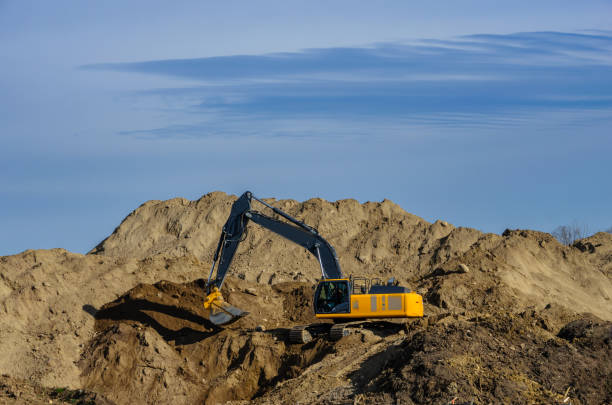 istock Excavator on a large dirt hill,  removing soil 2191489968