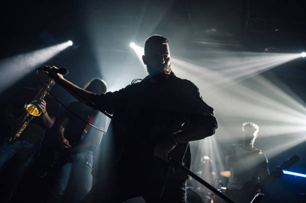 istock Singer performing with band on dark stage with bright lights 2191490150