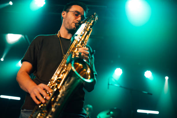 istock Saxophonist performing live on stage with teal lighting 2191490247