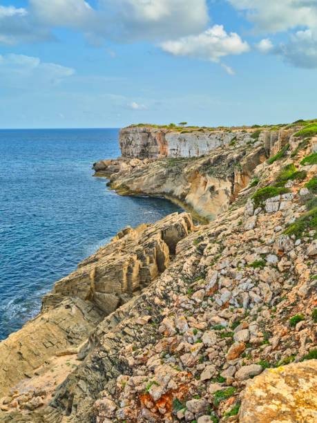 A serene view of Mallorca's rugged cliffs against the azure Mediterranean Sea. Captured in Spain, this scene depicts natural beauty with vibrant colors, rocky textures, and a sense of calm and tranquility.
