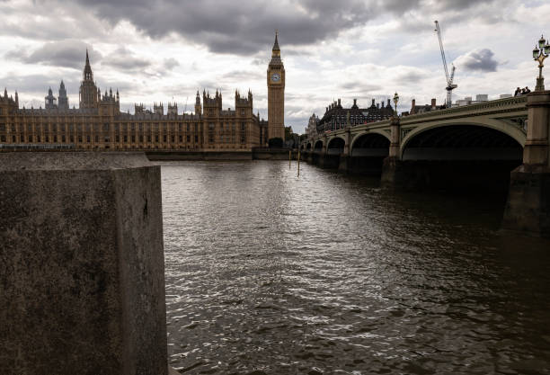 Westminster bridge crossing the river thames showcases the palace of westminster and elizabeth tower, known as big ben, under a dramatic cloudy sky in london