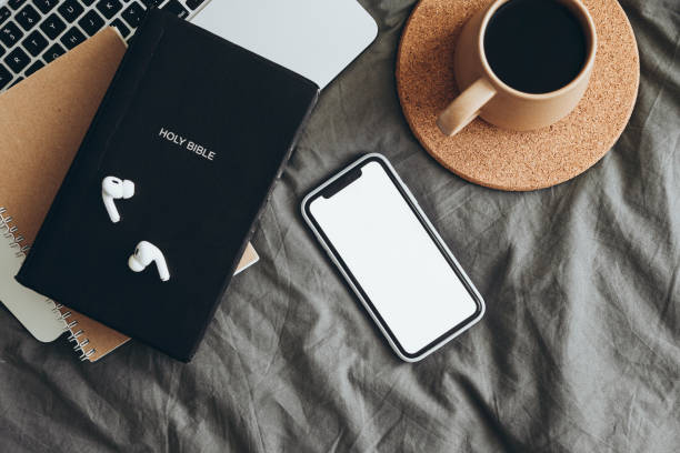 istock The Bible, phone with white blank screen on the bed, Holy book, online study. 2191495859