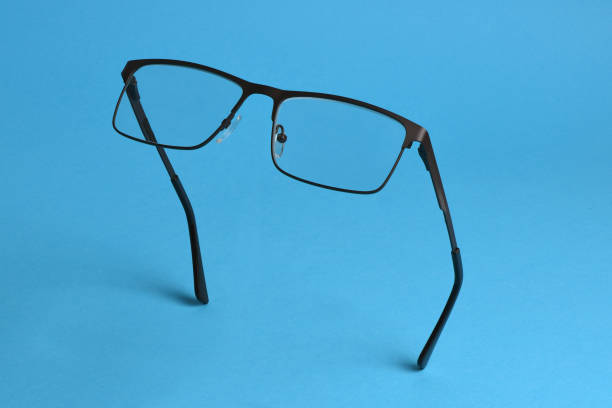 istock Reading glasses isolated on blue background. Glasses hang in air 2191500262