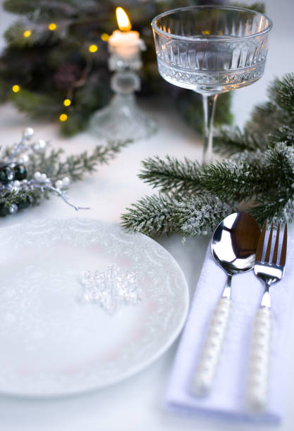 istock New Year's table setting in the restaurant. Fir branches and cutlery with a plate on a white background, a glass champagne glass 2191500972