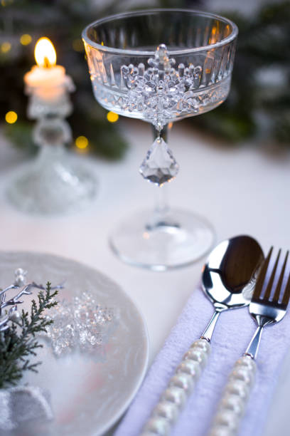 istock New Year's table setting in the restaurant. Fir branches and cutlery with a plate on a white background, a glass champagne glass 2191500973