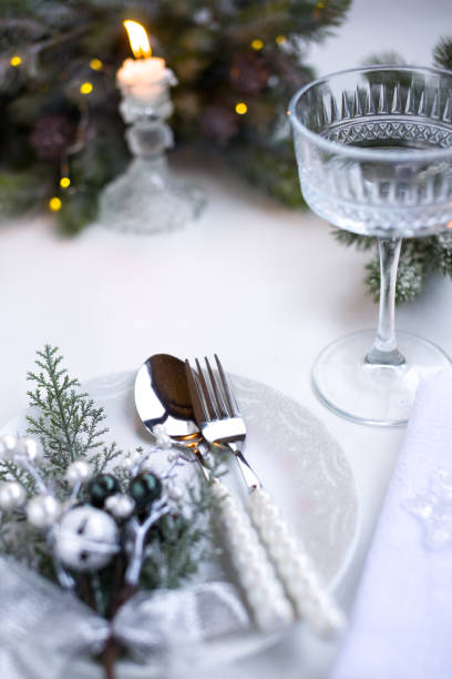 istock New Year's table setting in the restaurant. Fir branches and cutlery with a plate on a white background, a glass champagne glass 2191500974