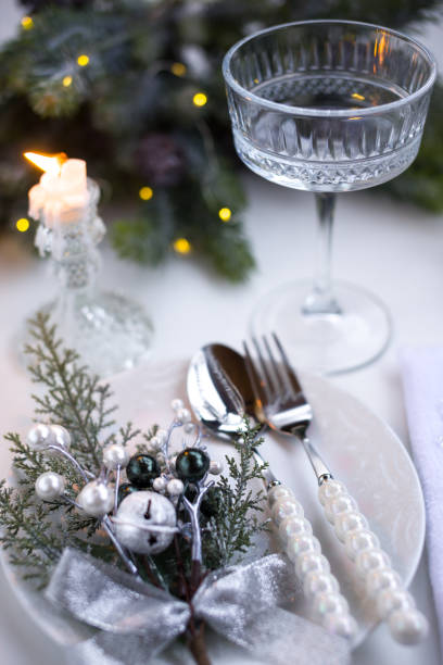 istock New Year's table setting in the restaurant. Fir branches and cutlery with a plate on a white background, a glass champagne glass 2191501008