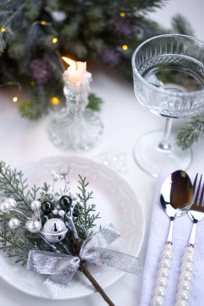 istock New Year's table setting in the restaurant. Fir branches and cutlery with a plate on a white background, a glass champagne glass 2191501009