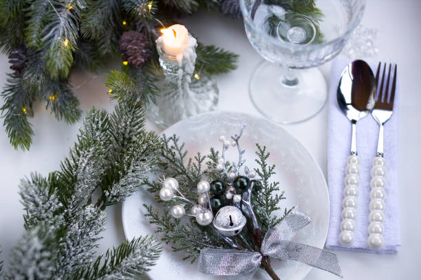 istock New Year's table setting in the restaurant. Fir branches and cutlery with a plate on a white background, a glass champagne glass 2191501546