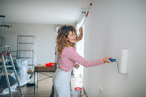 istock Happy Couple Painting a Wall with a Paint Roller 2191504397