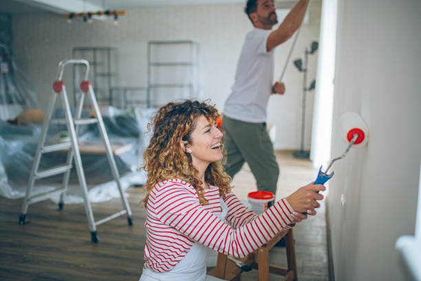 Happy Couple Painting a Wall with a Paint Roller