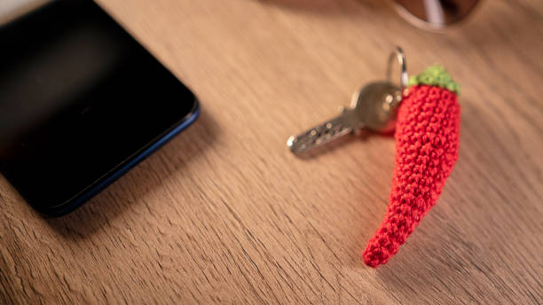 Red crocheted pepper keychain resting near smartphone