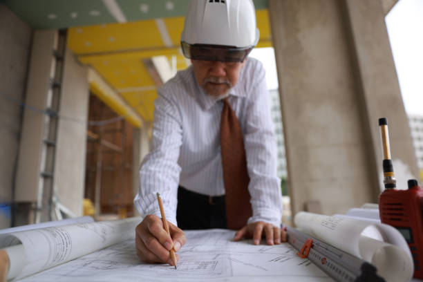 architect asian old man working with blueprints,engineer inspection in workplace construction site