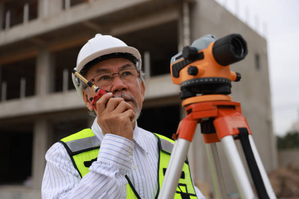 A Senior construction male engineer working with the theodolite camera at the housing  under construction
