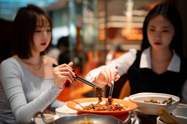 Asian young women eating dinner in Chinese restaurant