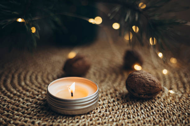 istock Burning candle, nuts and Christmas tree branches on a blurred bokeh background. 2191516989