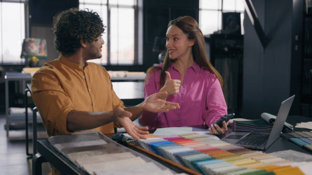 istock Multiracial couple creative designers work in modern office studio Arabian Indian man Caucasian woman using phone choosing perfect sample of material color tone for new house interior design project 2191526360