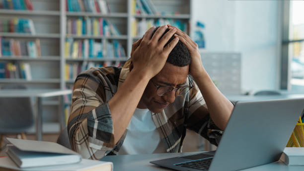 istock African American man student library laptop desktop computer gadget guy holding head tired overworked worker internet exhaustion anxiety lost connection problem deadline occupation male frustration pc 2191527430