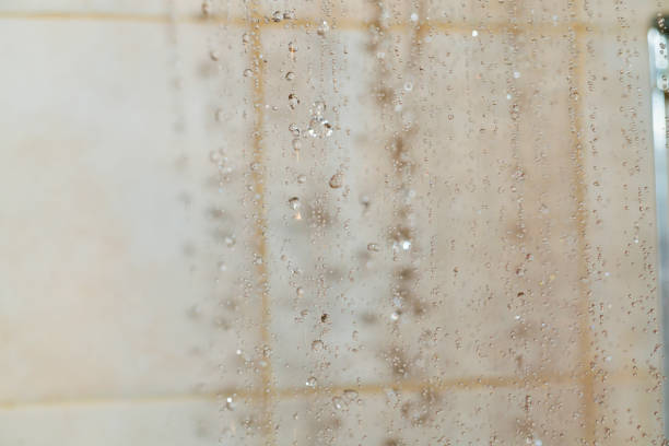 Water droplets fall gracefully from the surface in a bathroom, creating a serene atmosphere. Light reflects off the droplets, enhancing the tranquil feel.