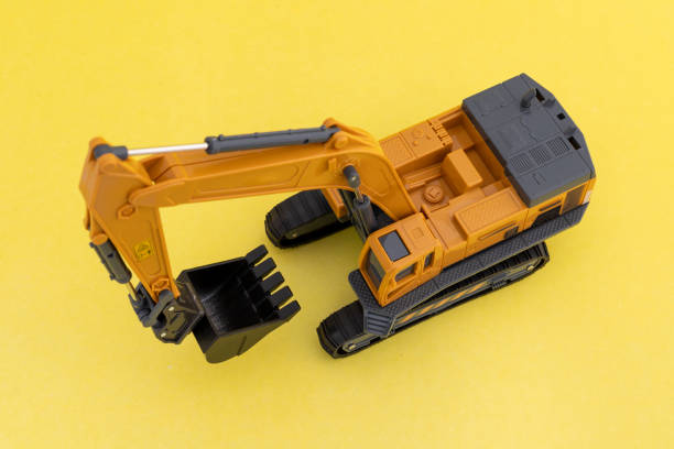 Miniature excavator scale model on yellow background. Top view.