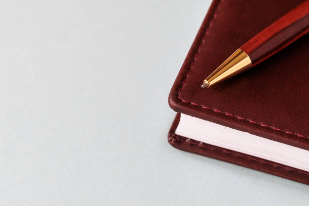 A brown leather diary and a fountain pen, resting on a white page. A blank space for writing.