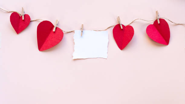 istock a string of hearts with a blank paper, hearts hanging on string, blank space for message, Valentine's day flat lay, creative pink background 2191538532