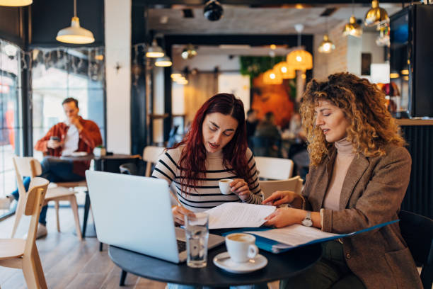 istock Two businesswomen analyzing documents while sitting on a coffee table in coffee shop. Woman executives discussing some paperwork 2191540577