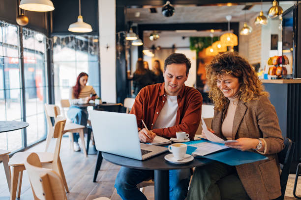 istock A businessman and a businesswoman are editing documents and using a laptop while sitting at a table in a coffee shop. Remote work and teamwork concept 2191540849