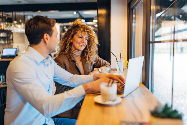 istock Two cheerful business colleagues dressed in smart casual clothes work remotely from coffee shop 2191542407