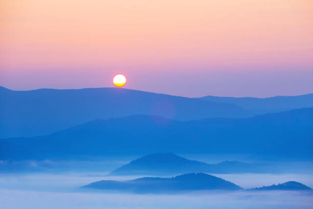 mountain chain silhouette in dense mist at the sunrise
