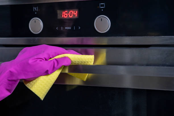 istock Wiping oven surface with yellow cloth and pink gloves during cleaning process 2191546062