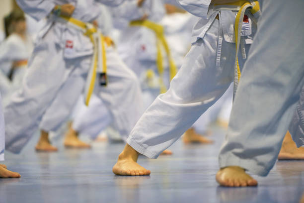istock Close-up of martial arts students practicing stances in white uniforms with yellow belts 2191546292