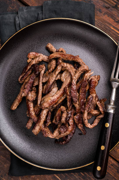 istock BBQ Fried beef tender strips, sliced steak in a plate. wooden background. top view 2191547381