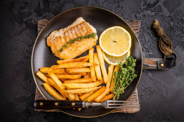 istock Homemade Fish and chips with roast cod whitefish fillet and fried potatoes on plate. black background. top view 2191548055